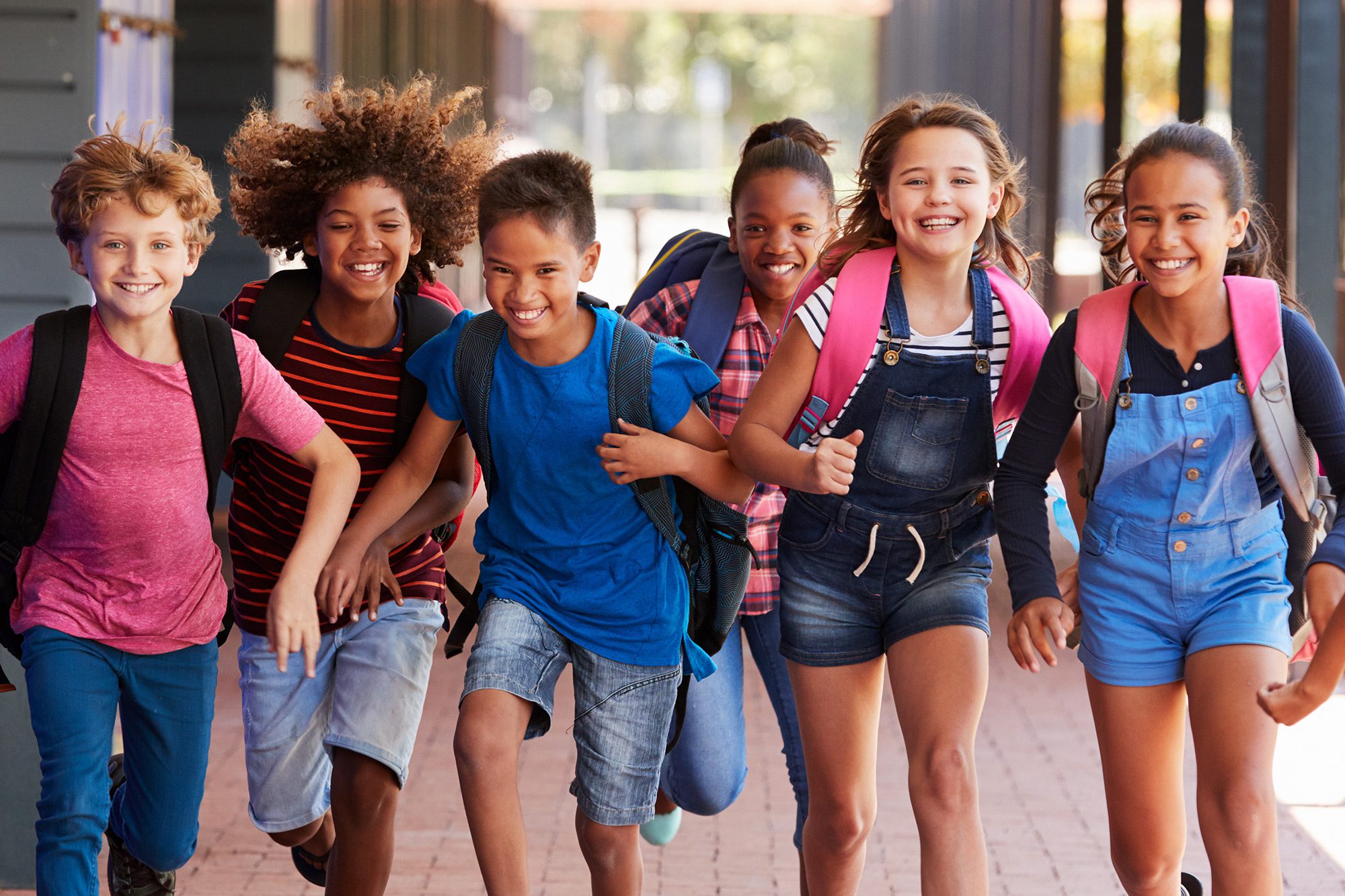 Diverse students happily running in school