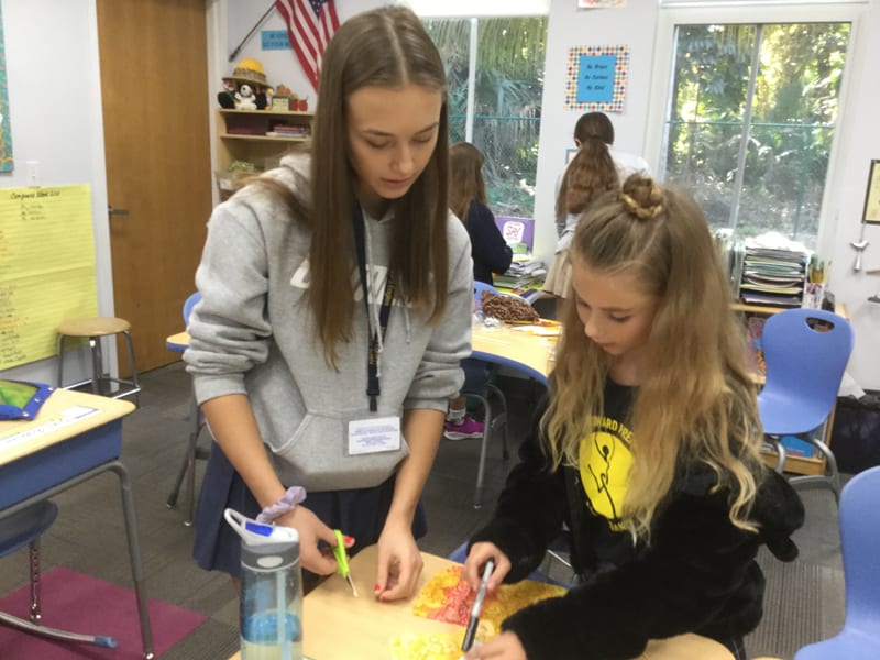 Lena, a member of the Youth Advisory Board, helps an elementary school student create a doll as part of a recent diversity exercise.