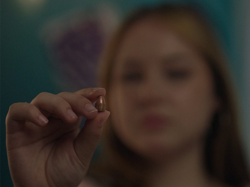 Hannah holds the bullet that killed her best friend. She was shot by the same bullet which ended up in her ribcage.