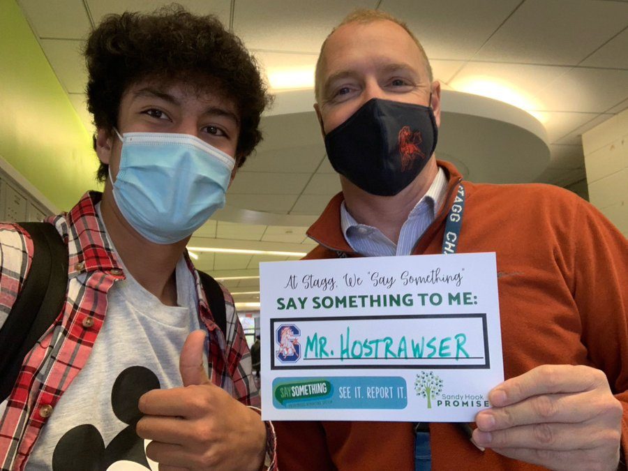 Student and teacher holding a "Say Something to me" sign
