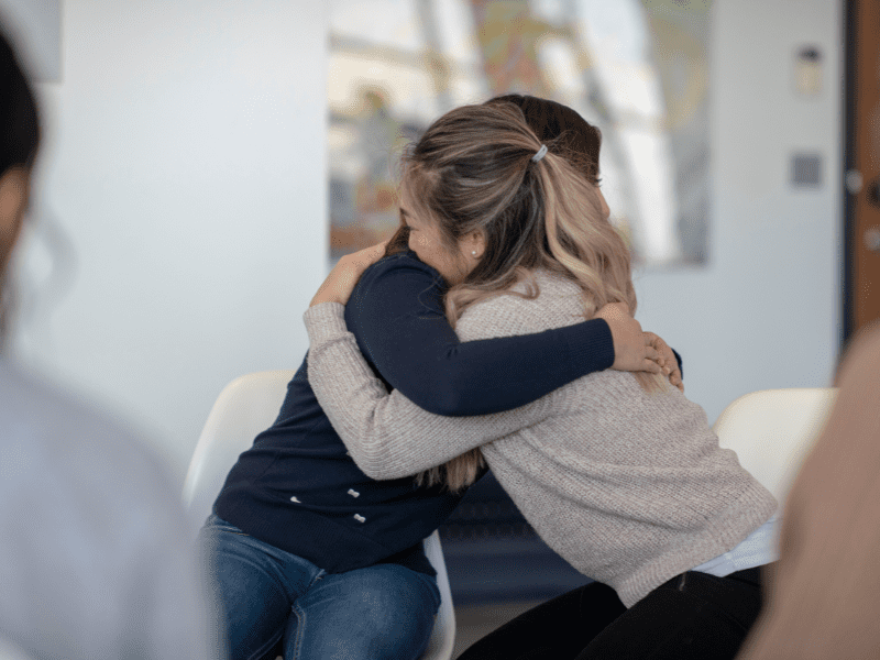 Two women hugging each other during a group therapy class.