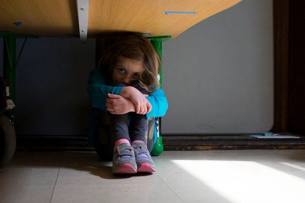 Little girl hiding under a desk